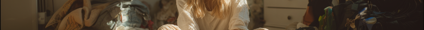 Beautiful blonde woman sitting in messy bedroom