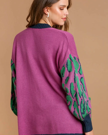 Woman wearing a purple sweater with green patterned sleeves on a beige background