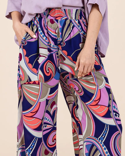 Person wearing colorful patterned pants with a plain background