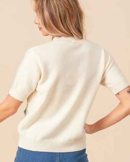 Woman wearing a cream sweater and blue jeans against a beige background