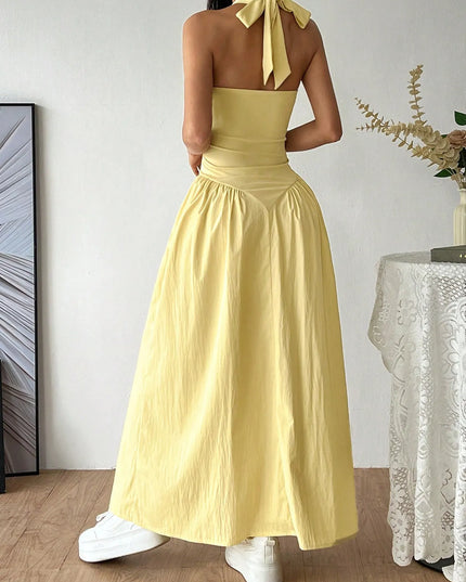 Woman wearing a yellow dress with a halter neck in a room.