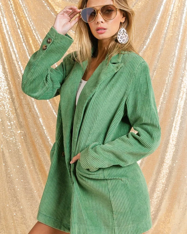 Woman wearing The Vintage Moss Blazer with sunglasses against a gold glittery background