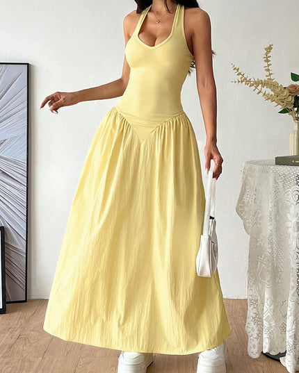 Woman wearing a yellow dress standing in a room with a white wall and decorative elements.