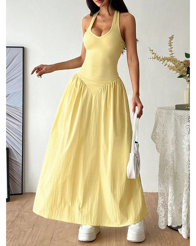 Woman wearing a yellow dress standing in a room with a white wall and decorative elements.
