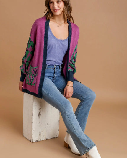 Woman wearing a colorful cardigan, blue jeans, and white boots on a beige background