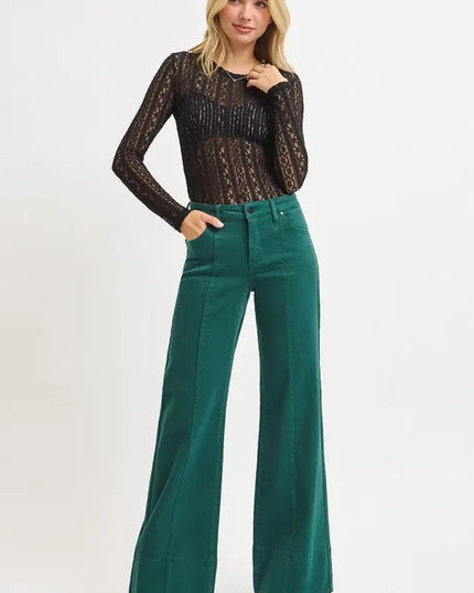 Woman wearing a black lace top and emerald high-waisted pants on a white background