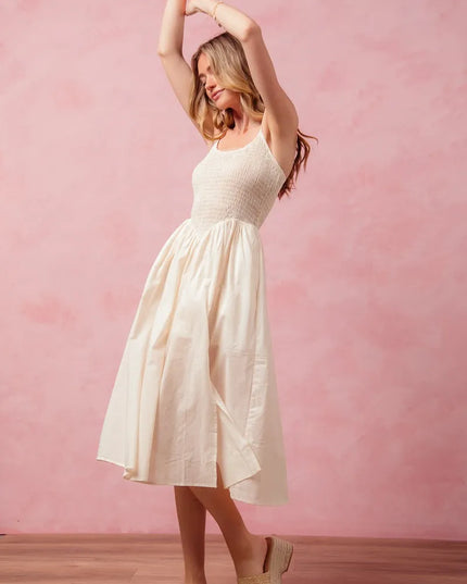 Woman in a white dress posing against a pink wall