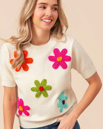 Woman wearing a white sweater with colorful flower patterns on a beige background