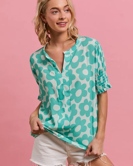 Woman wearing a Turquoise Bloom Notched Collar Blouse and white shorts against a pink background