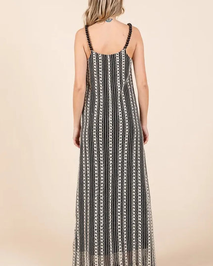 Woman wearing a black and white patterned maxi dress on a beige background