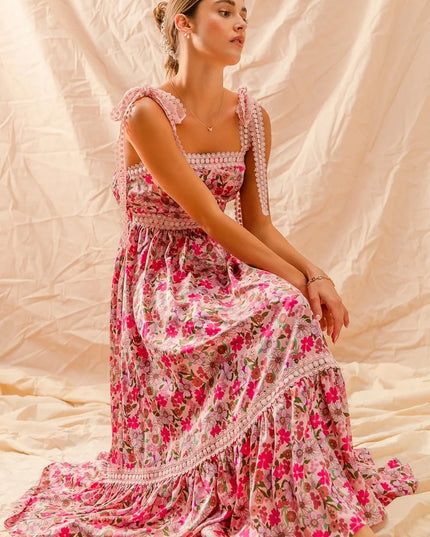 Woman wearing a Wild Bloom Smocked Maxi Dress sitting on a textured beige background