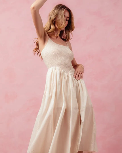 Woman in a white dress posing against a pink background