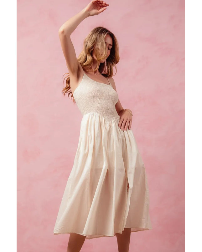 Woman in a white dress posing against a pink background