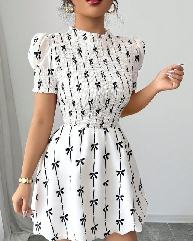 White dress with black bow pattern worn by a woman against a neutral background