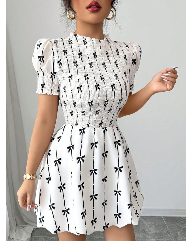 White dress with black bow pattern worn by a woman against a neutral background