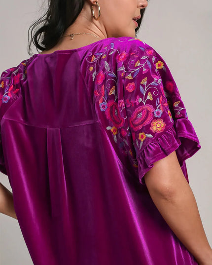 Purple blouse with floral embroidery on sleeves against a neutral background