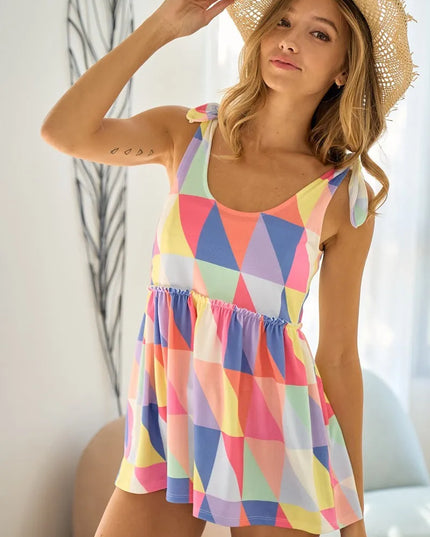 Woman wearing a colorful geometric patterned top and straw hat indoors.