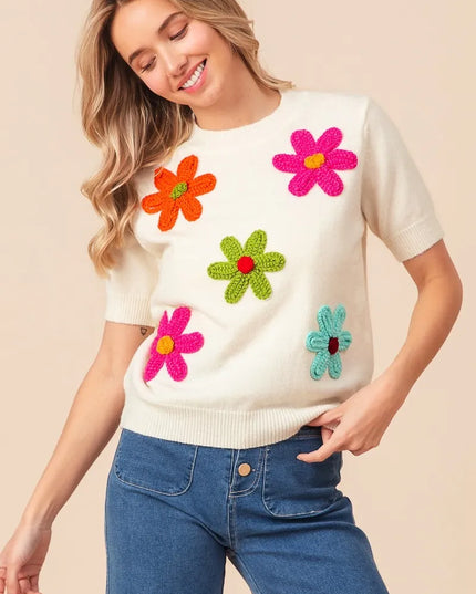 Woman wearing a white sweater with colorful flower patterns on a beige background