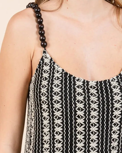 Black and white patterned dress with a beaded strap on a neutral background