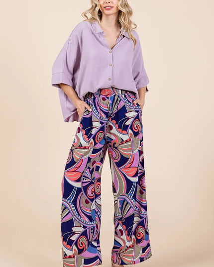Woman wearing a light purple shirt and colorful patterned pants on a beige background