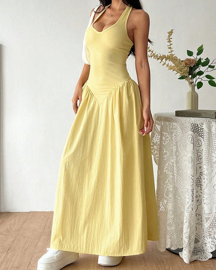 Woman wearing a yellow dress standing indoors with a decorative plant in the background
