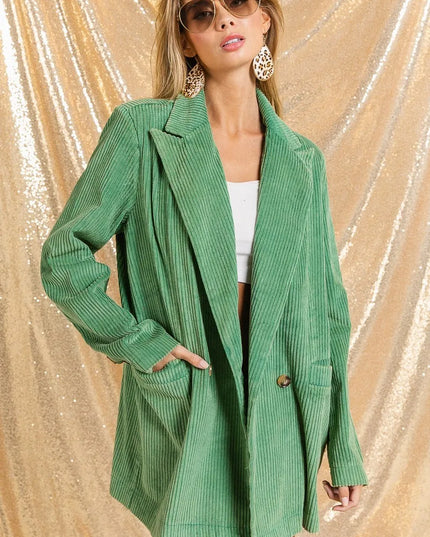 Woman wearing The Vintage Moss Blazer over a white top against a gold glittery background