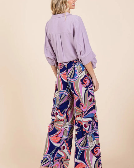 Woman wearing a light purple blouse and colorful patterned pants on a beige background