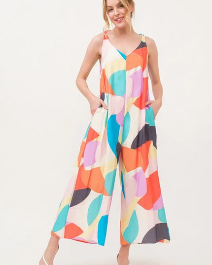 Woman wearing a colorful geometric patterned jumpsuit on a white background
