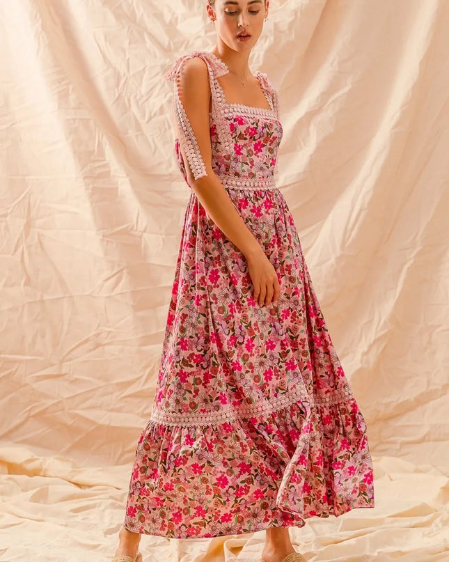 Woman wearing a Wild Bloom Smocked Maxi Dress against a beige fabric background